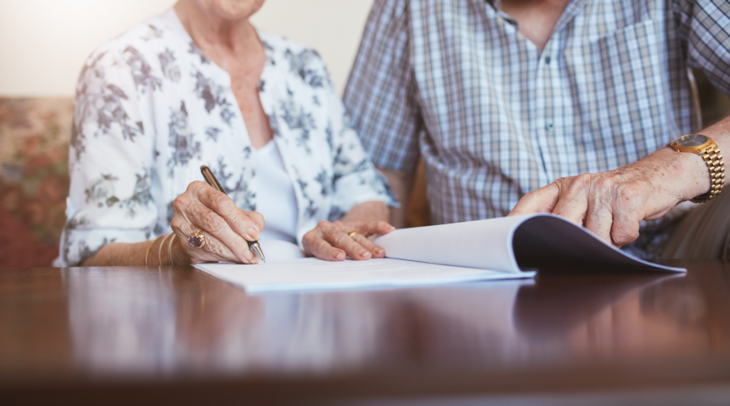 an older couple reads over and signs an important document