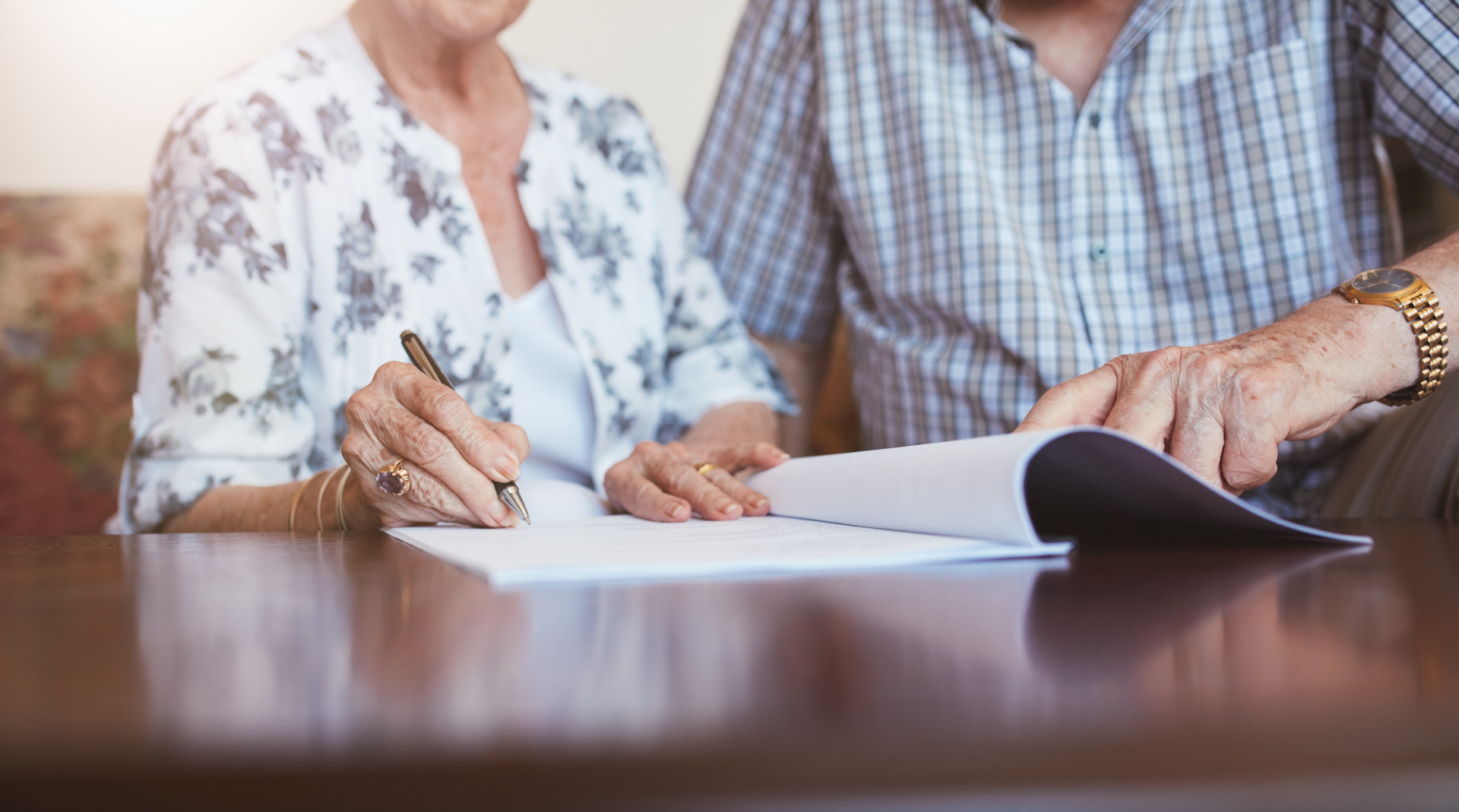 an older couple reads over and signs an important document